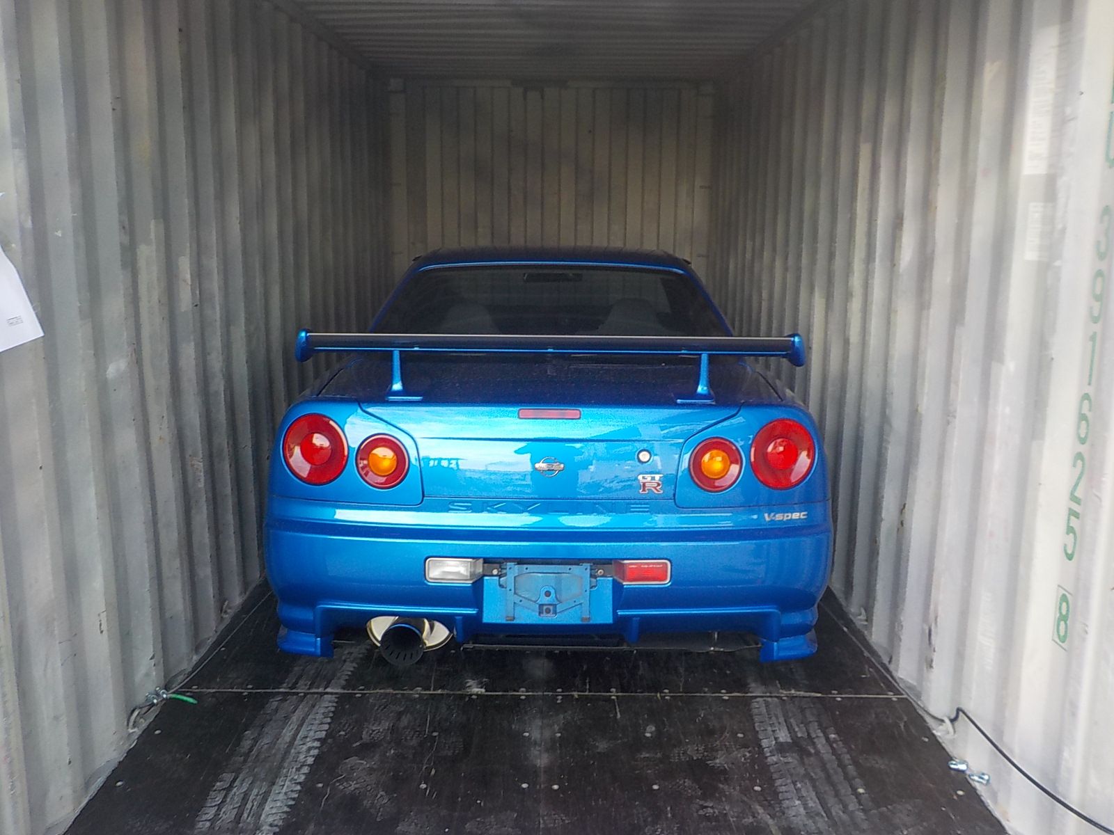 A blue Japanese sports coupe inside a shipping container